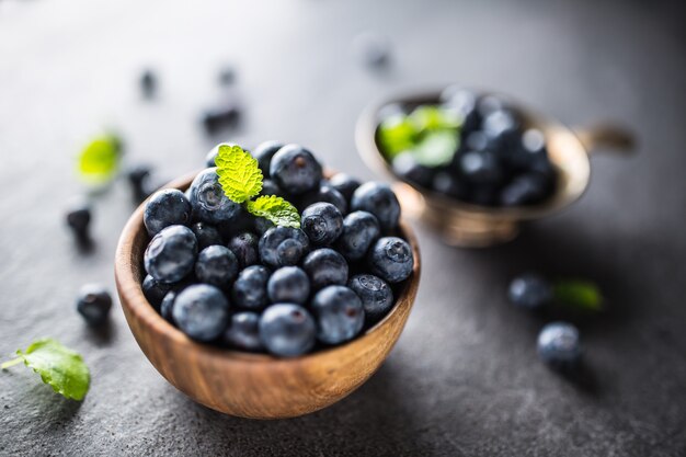 Holzschale voller frischer Blaubeeren mit Kräutern.