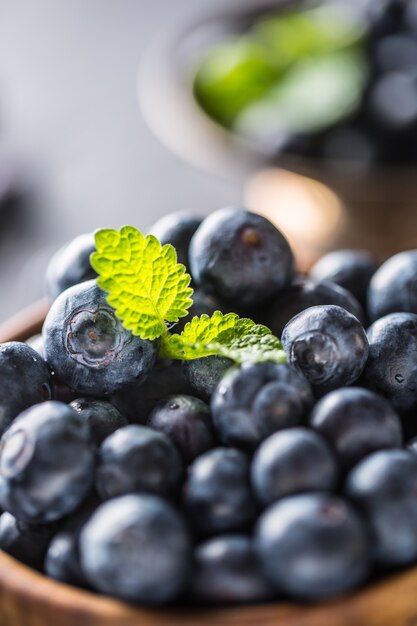 Holzschale voller frischer Blaubeeren mit Kräutern.