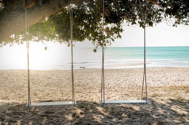 Holzschaukel unter Baum am Strand