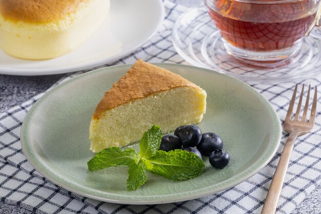 Holzschreibtisch mit japanischem Käsekuchen und Nachmittagstee, Nahaufnahme.