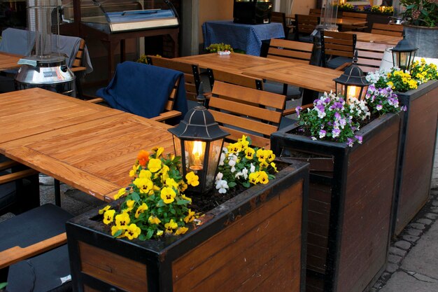 Holzstände mit kleinen Frühlingsblumen und großen Metallstraßenlaternen Straßencafé