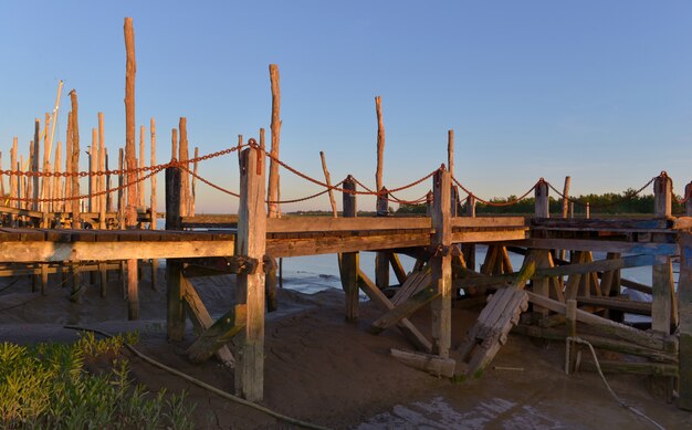 Holzstangen und Pontonbeleuchtung durch Sonne bei Sonnenuntergang im Atlantik