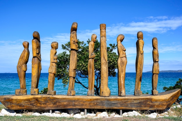 Holzstatue von Menschen auf einem Boot durch das Meer in Nea Roda, Chalkidiki, Griechenland