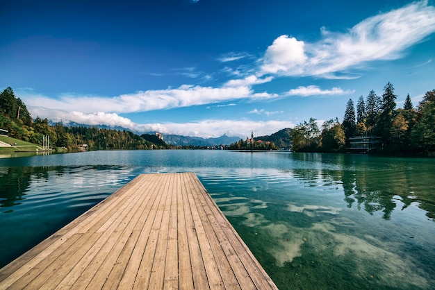 Holzsteg Bleder See, Slowenien mit blauem Himmel und Wolken im Herbst