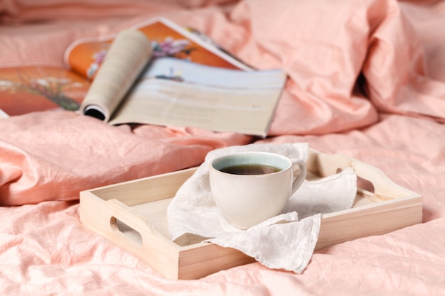 Holztablett mit leckerem Frühstück auf dem Bett