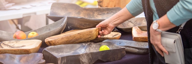 Holzteller Große Teller und Tabletts bestehen aus exotischen Hölzern in verschiedenen Farben. Der Käufer wählt Holzutensilien auf dem Markt, dem Konzept des Handwerks und des Kleingewerbes