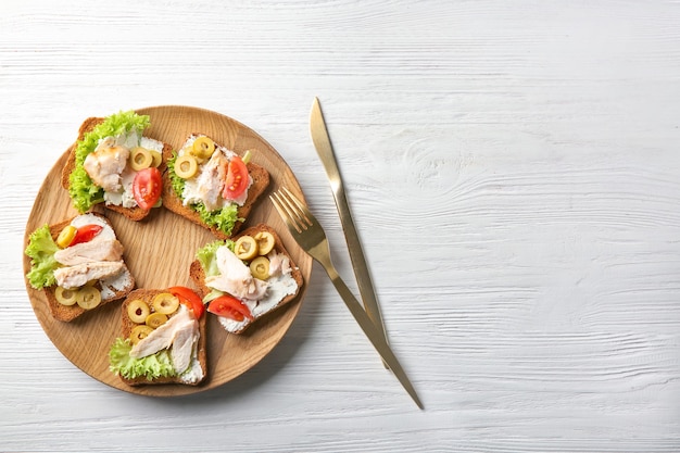 Holzteller mit leckeren Hühnchen-Bruschettas auf dem Tisch