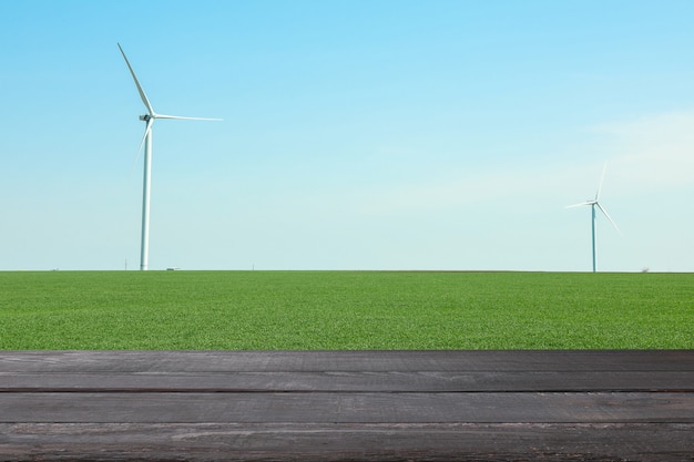 Holztisch gegen Feld mit Windmühlen. Landwirtschaftskonzept. Attrappe, Lehrmodell, Simulation