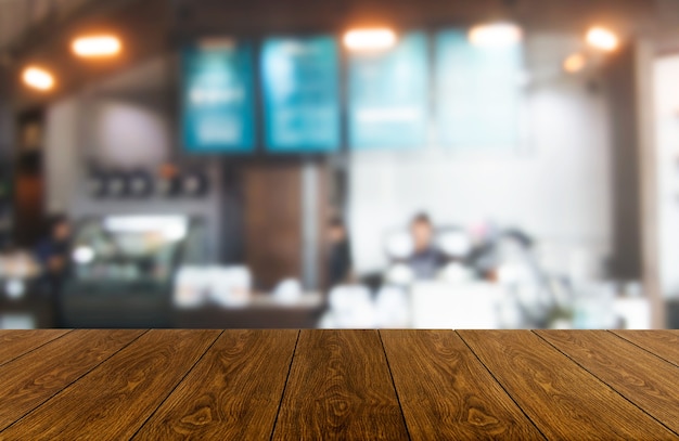 Holztisch im verschwommenen Hintergrund des modernen Restaurantraums oder des Kaffeehauses für Produktanzeigemodell.