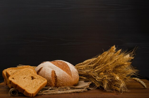 Holztisch mit rundem und quadratischem Roggenbrot, eine Garbe