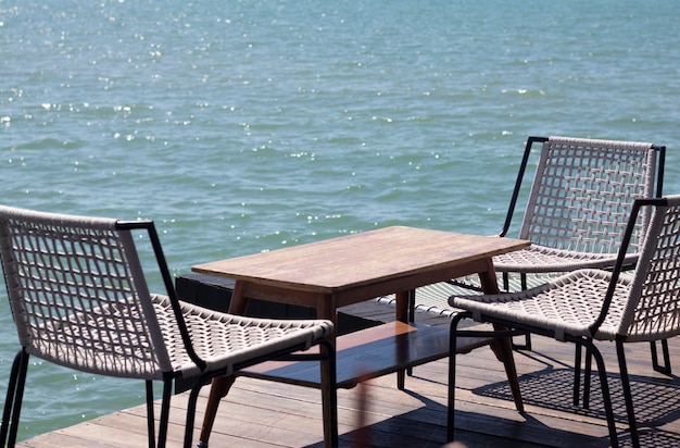 Holztisch mit Stühlen und Liegestühlen. Hintergrund des Meeres.
