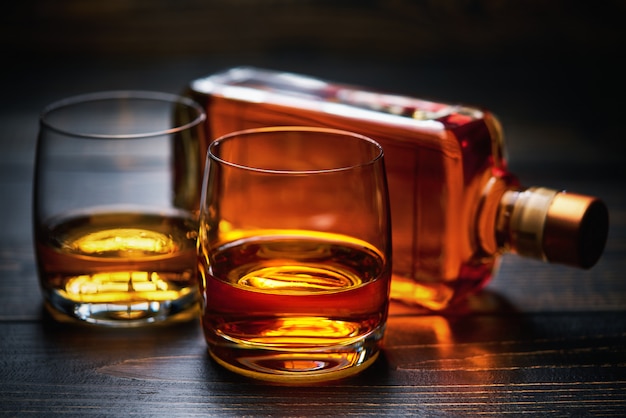 Foto holztisch mit zwei schüssen whisky und voller flasche