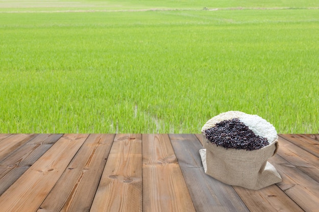 Holztisch und Jasminreis mit grünem Paddy-Reisfeld-Hintergrund