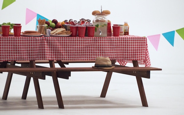 Holztisch und rote Serviettenabdeckung für Party im Freien oder Picknick im Garten für die Sommersaison und weißen Hintergrund.