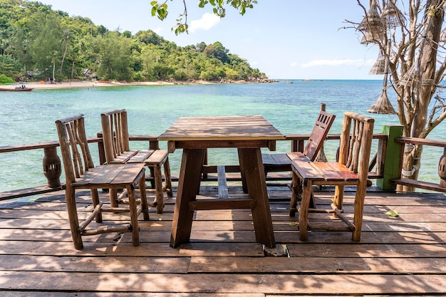 Holztisch und Stühle in leerem Strandcafé neben Meerwasser Nahaufnahme der Insel Koh Phangan Thailand