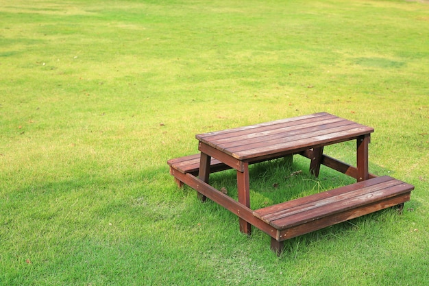 Holztisch und Stühle stellten auf grünen Rasen im Garten ein.