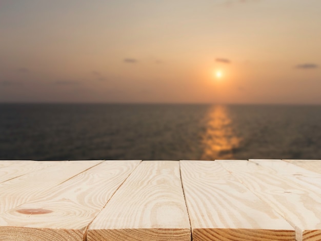 Holztisch vor abstrakter verschwommener Sicht auf den Sonnenuntergang über dem Meereshintergrund