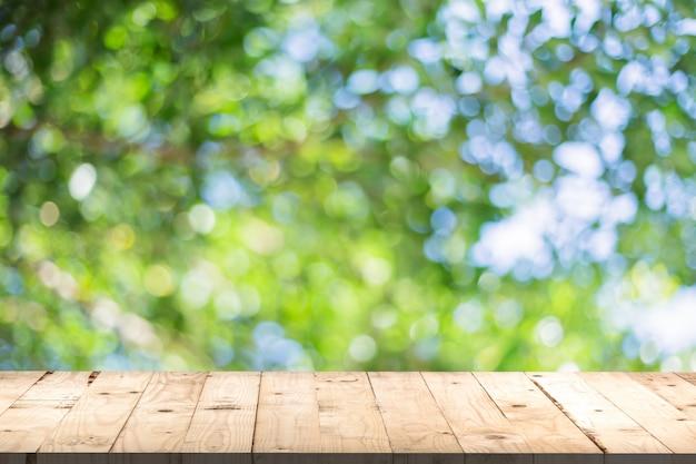 Holztischperpertive und grünes Blatt bokeh verwischt für natürlichen Hintergrund