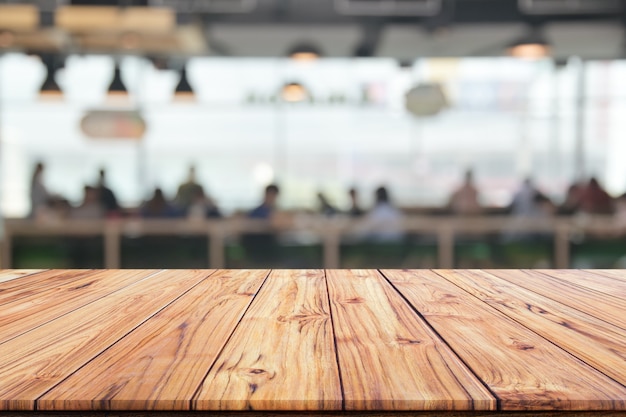 Holztischplatte auf unscharfem Hintergrund des Innencafés oder Restaurant verwischen Cafécaféhintergrunds