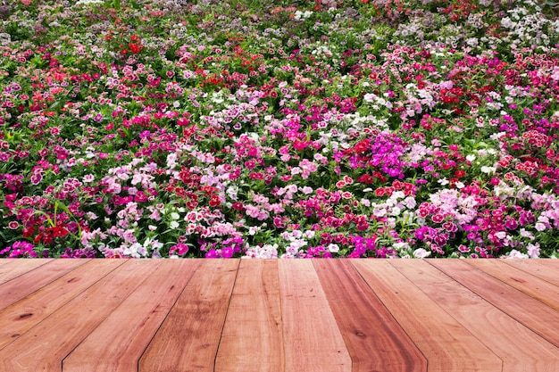 Holztischspitze und rosa Blumenhintergrund.