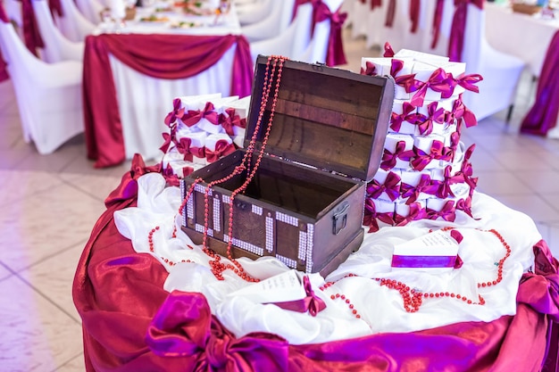 Holztruhe auf dem Tisch mit violetter Tischdecke und kleinen Gastgeschenken vom Brautpaar