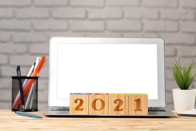 Holzwürfel 2021 Jahr auf Arbeitstisch mit offenem Laptop
