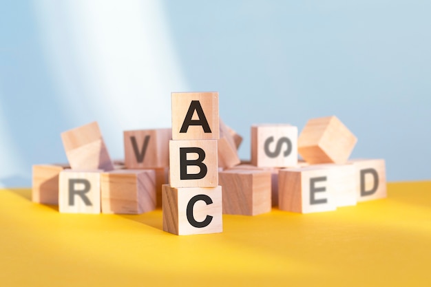 Holzwürfel mit Buchstaben ABC in einer vertikalen Pyramide angeordnet, grauer und gelber Hintergrund, Geschäftskonzept. sla – kurz für Service Level Agreement