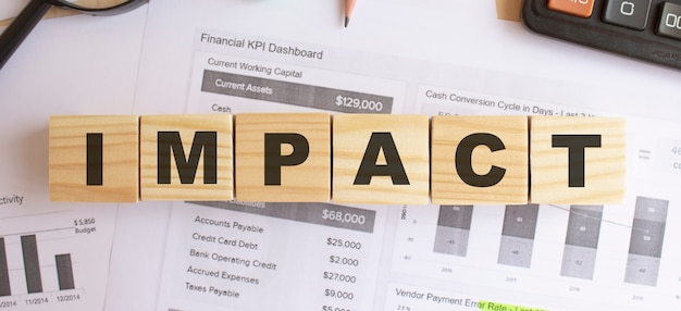 Holzwürfel mit Buchstaben auf dem Tisch im Büro. Text IMPACT. Finanzkonzept.