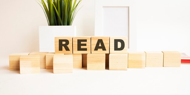 Holzwürfel mit Buchstaben auf einem weißen Tisch Das Wort ist LESEN Weißer Hintergrund