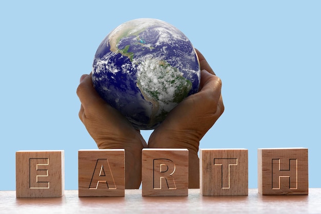 Holzwürfel mit dem Wort Erde mit Hintergrund von Händen, die Planeten halten