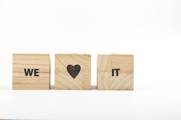 Holzwürfel mit der Aufschrift „Wir lieben es“ auf weißem Hintergrund in Großaufnahme