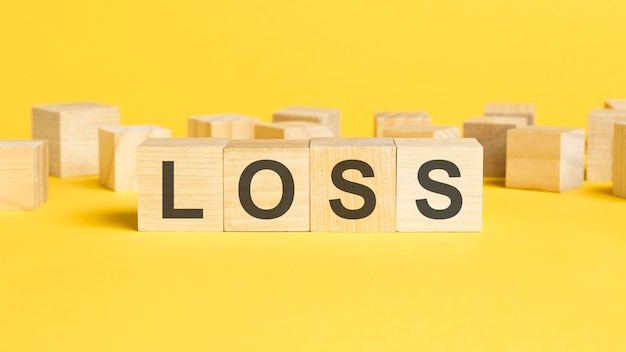 Holzwürfel mit LOSS-Wort auf gelbem Hintergrund Geschäftskonzept für finanzielle Verluste