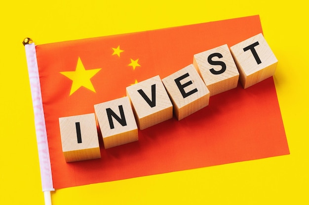 Holzwürfel mit Text und einer Flagge auf farbigem Hintergrund das Konzept der Investition aus China