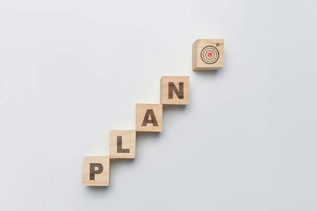 Holzwürfelblöcke mit dem Wort PLAN mit Ziel-Symbol auf weißem Hintergrund Ziele des Geschäftsaktionsplans Ziele und Strategiekonzept