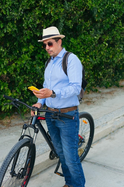 Hombre de 40 años revisa su celular mientras anda en bicicleta en la ciudad