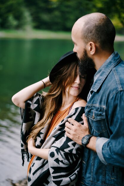 El hombre abraza los hombros de una mujer embarazada cerca del retrato del lago