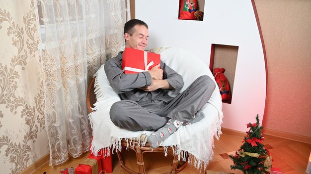 Un hombre abraza un regalo de Año Nuevo, con una sonrisa en su rostro. Foto de alta calidad