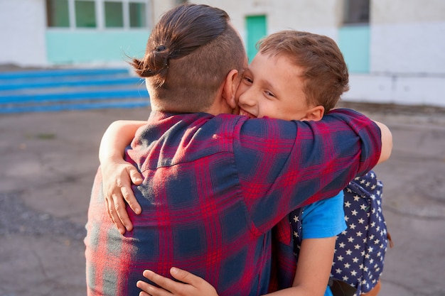 Foto el hombre abraza a su hijo antes de ir a la escuela