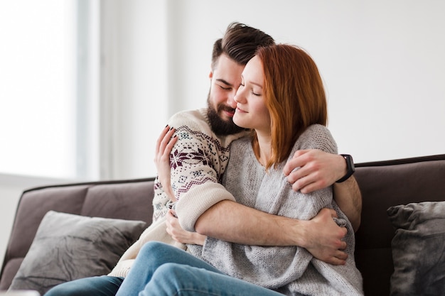 Foto hombre abrazando a su novia en la sala de estar