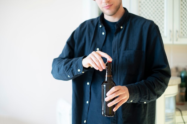 Un hombre abre la botella de cerveza de vidrio en la fiesta, mal hábito, adicto al alcohol