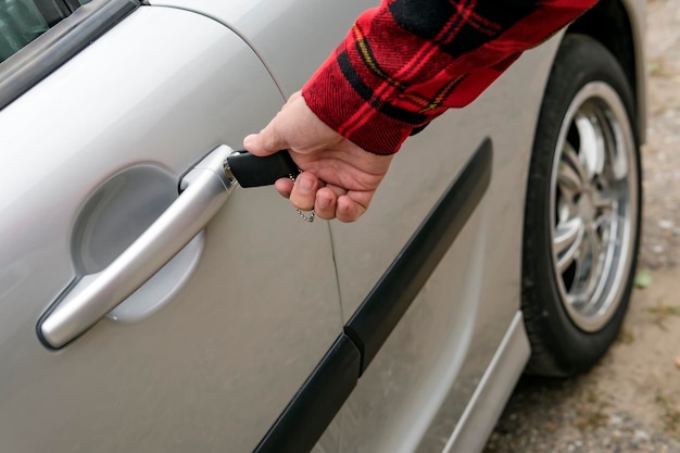 El hombre abre mecánicamente su automóvil insertando la llave Girando la llave en el ojo de la cerradura en la manija de la puerta de un vehículo estacionado La persona diestra tiene la intención de abrir el automóvil Bloqueando o desbloqueando la puerta del motor