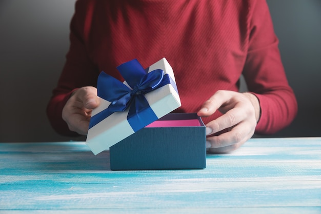 El hombre abre un regalo sobre la mesa