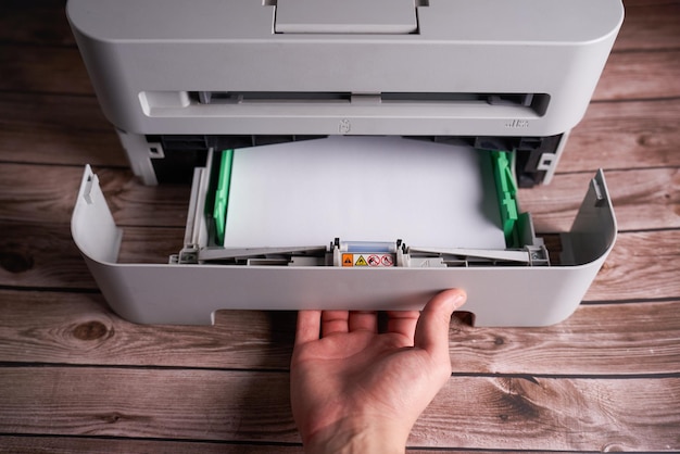 hombre abriendo una bandeja de papel de impresora