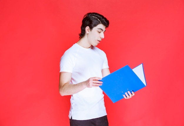 Hombre abriendo y leyendo una carpeta azul.