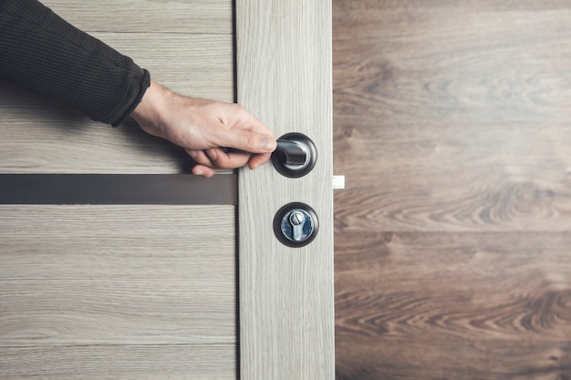 Hombre abriendo la puerta de madera de la habitación.