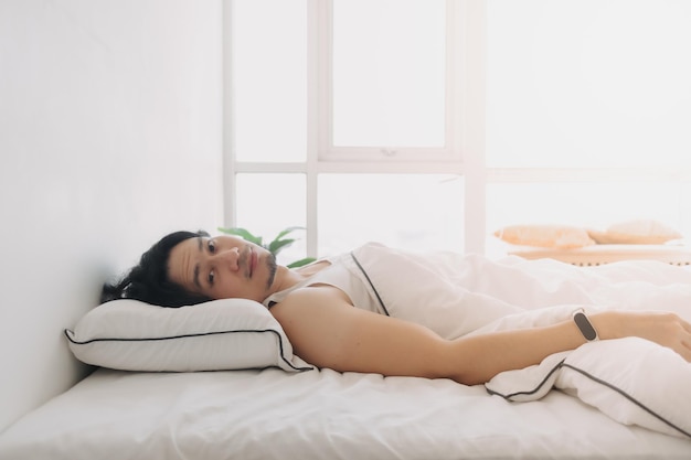 El hombre acaba de despertar en una mañana feliz en el dormitorio blanco brillante