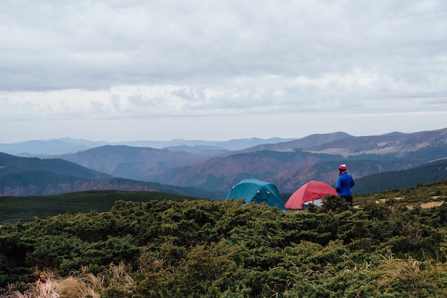 Foto hombre acampando en una montaña con hierba verde