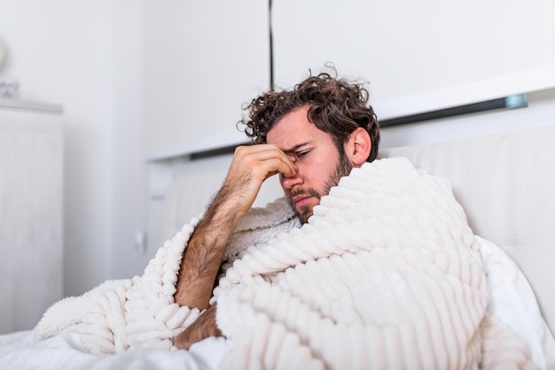 Hombre acostado en la cama en casa que sufre de dolor de cabeza o resaca, enfermedad, concepto de problema de virus estacional. Coronavirus (COVID-19
