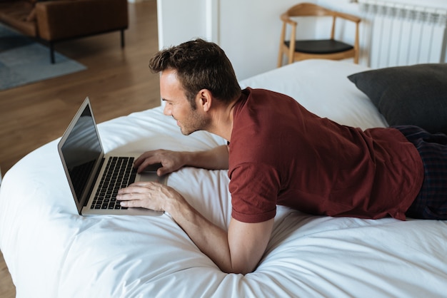 Hombre acostado en la cama con una computadora