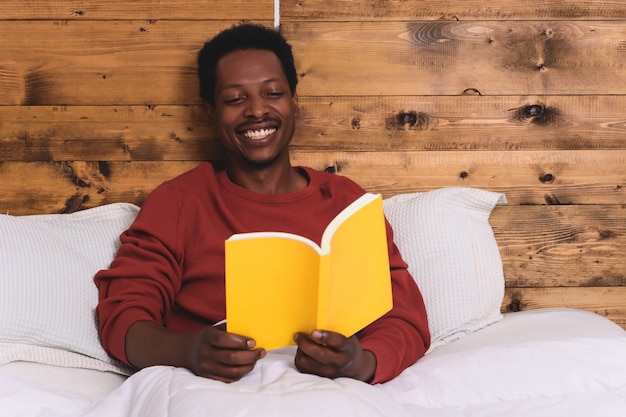 Hombre acostado en la cama y leyendo el libro